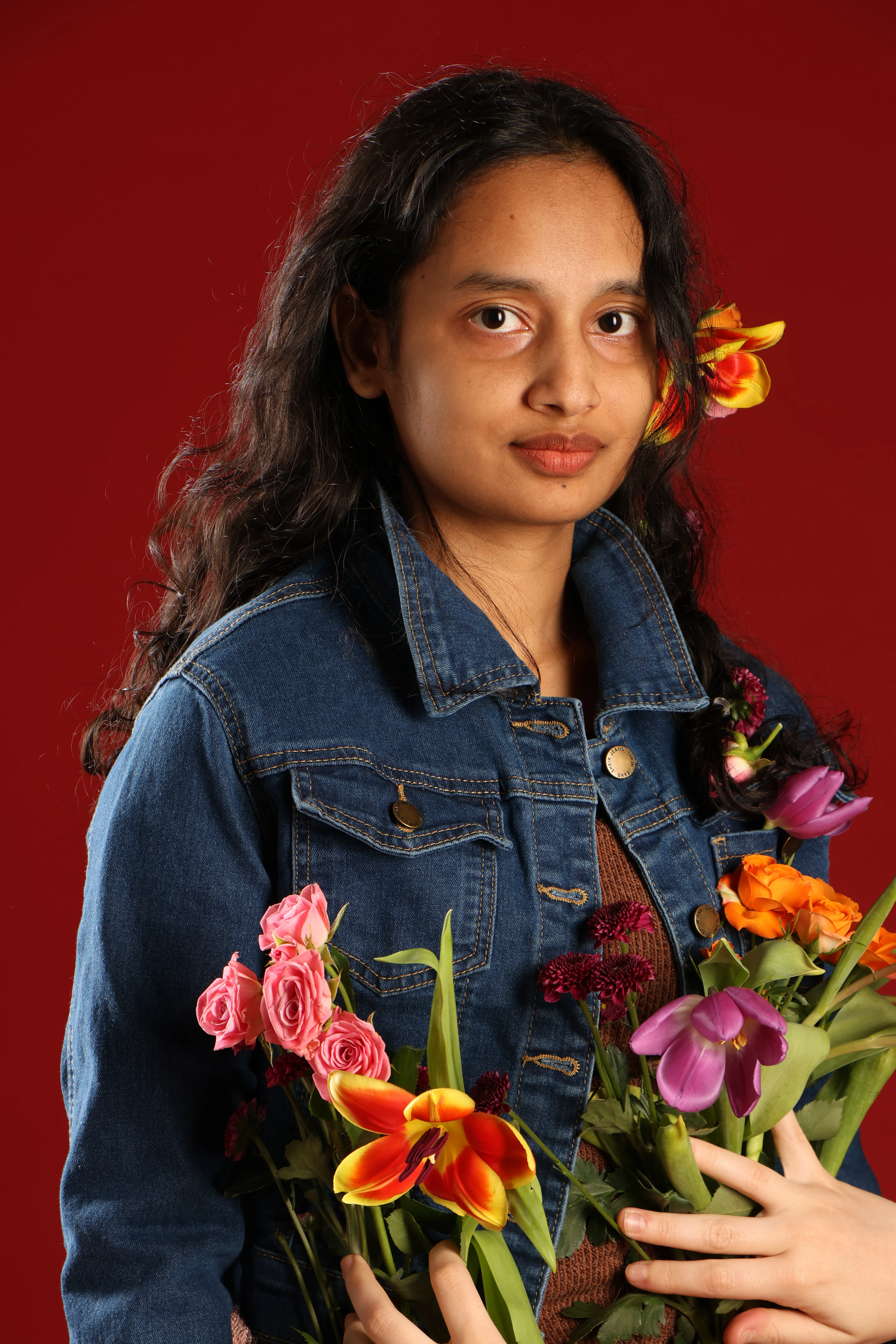 Rownok Jahan Tithi in a denim jacket, holding pink roses — studio portrait